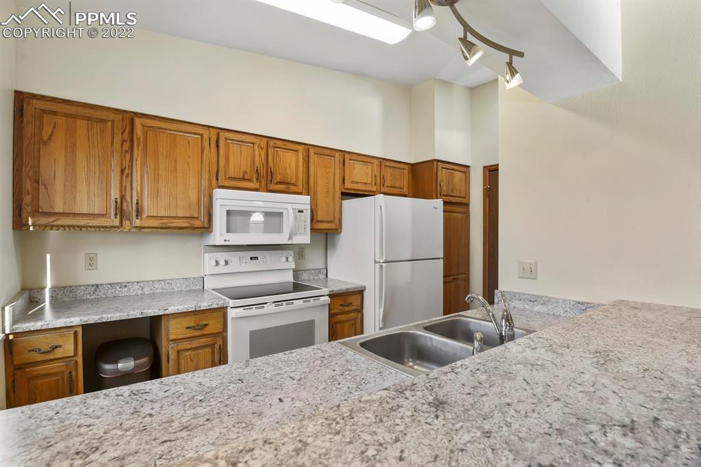 1130 Fontmore Road, Unit C Colorado Springs, CO 80904 - Photo 11 of 27 a kitchen with kitchen island granite countertop a stove a sink dishwasher and a refrigerator