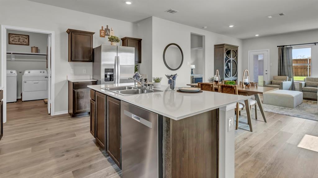124 Pheasant Run Road Terrell, TX 75160 - Photo 21 of 35 Open-concept living space featuring wood-finish flooring, a kitchen island with a double basin sink, stainless steel appliances, dark wood cabinetry, and recessed lighting