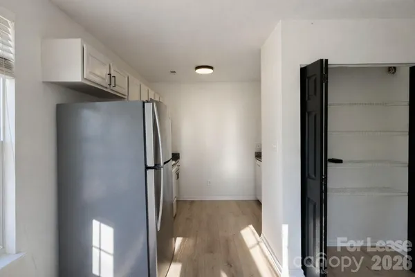 a view of a refrigerator in kitchen and an empty room