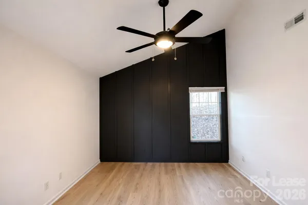 an empty room with windows and fan