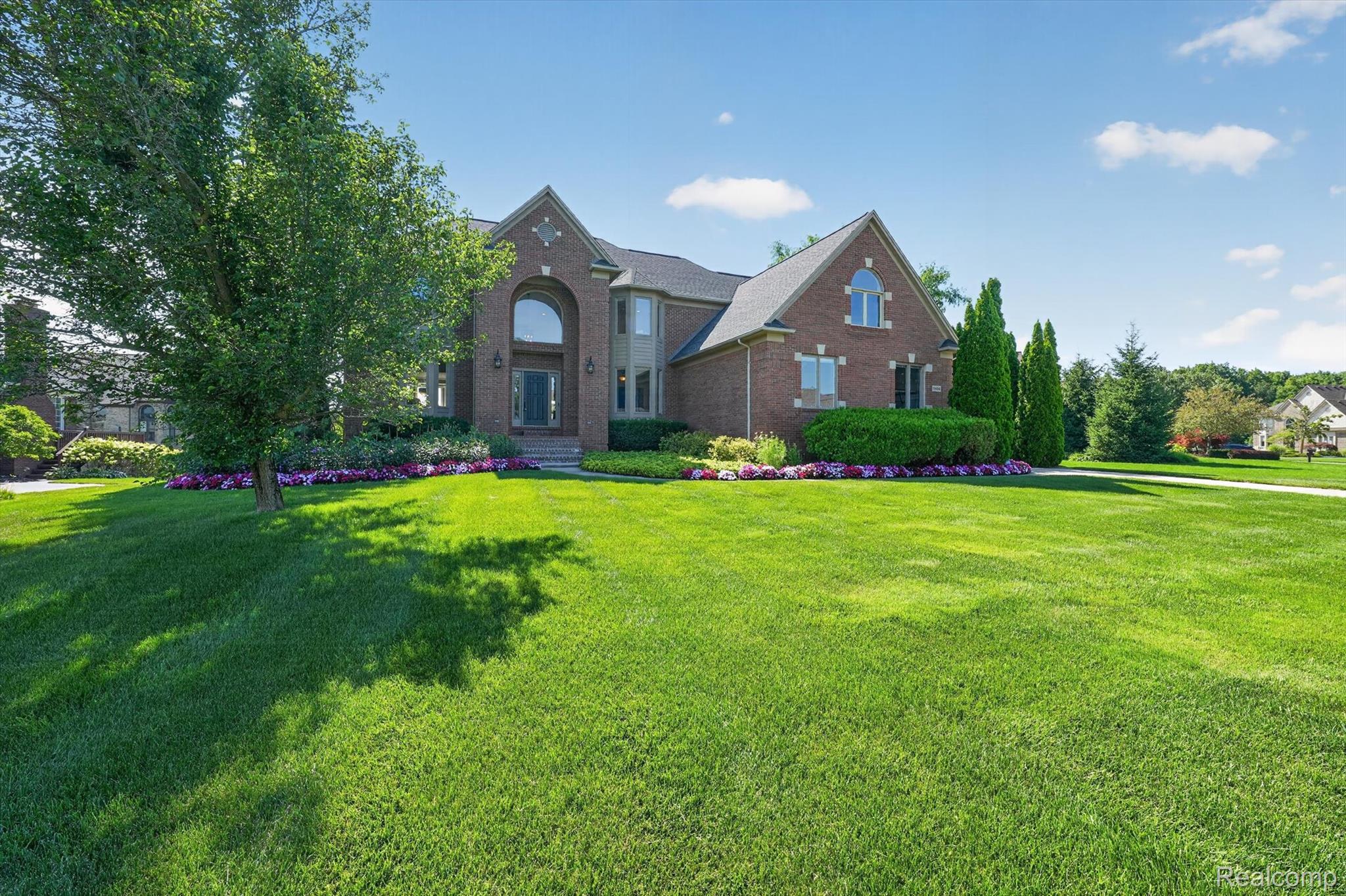 3804 Elk Drive Rochester, MI 48306 - Photo 3 of 75 Brick exterior featuring an arched window above the main entry, a gabled roofline, and landscaped foundation plantings