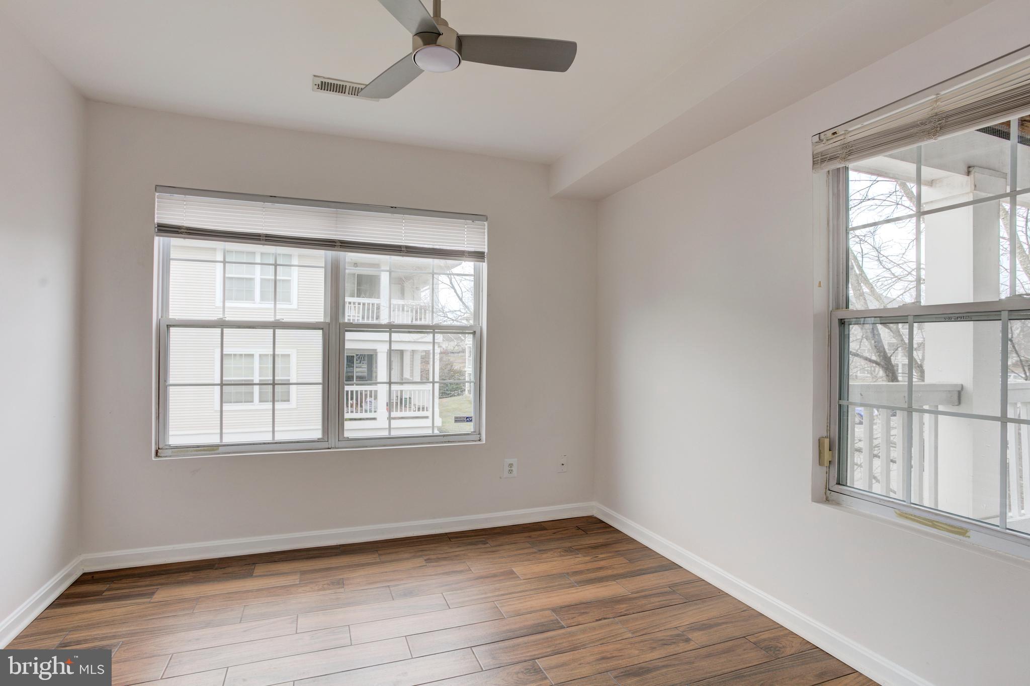 14174 Cuddy Loop, Unit 204 Woodbridge, VA 22193 - Photo 22 of 24 an empty room with wooden floor and windows