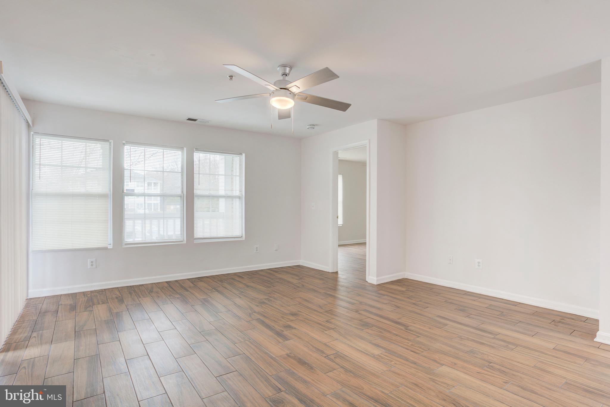 14174 Cuddy Loop, Unit 204 Woodbridge, VA 22193 - Photo 4 of 24 an empty room with wooden floor fan and windows