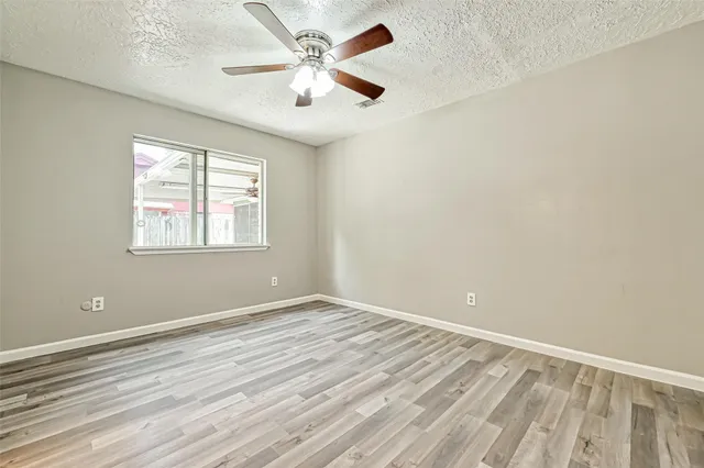 an empty room with a window and ceiling fan