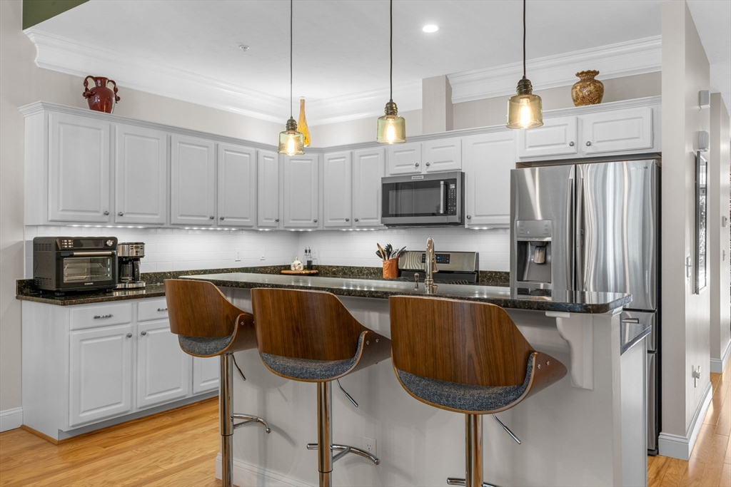 116 Grey Hawk Drive, Unit 116 Mashpee, MA 02649 - Photo 9 of 41 a kitchen with stainless steel appliances granite countertop a stove a sink a microwave a refrigerator and cabinets