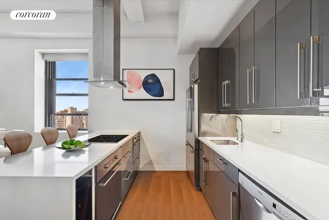 a living room with couches chairs and kitchen view with wooden floor