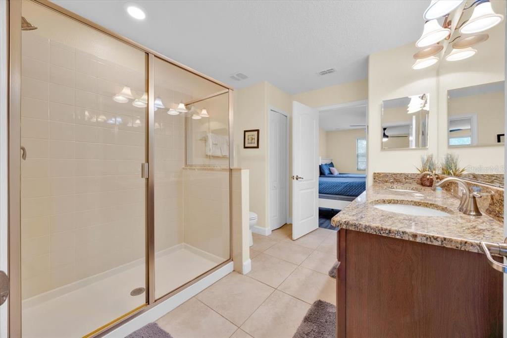 9032 Shadow Mountain Street Davenport, FL 33896 - Photo 23 of 43 a spacious bathroom with a granite countertop sink a mirror and shower