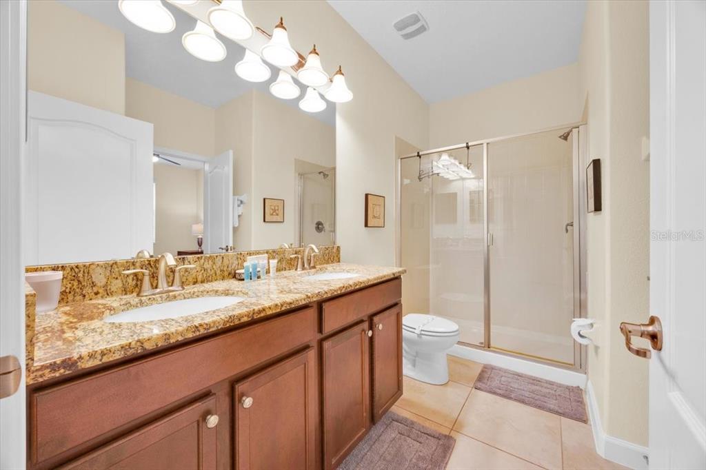 9032 Shadow Mountain Street Davenport, FL 33896 - Photo 6 of 43 a bathroom with a granite countertop sink a toilet and a mirror
