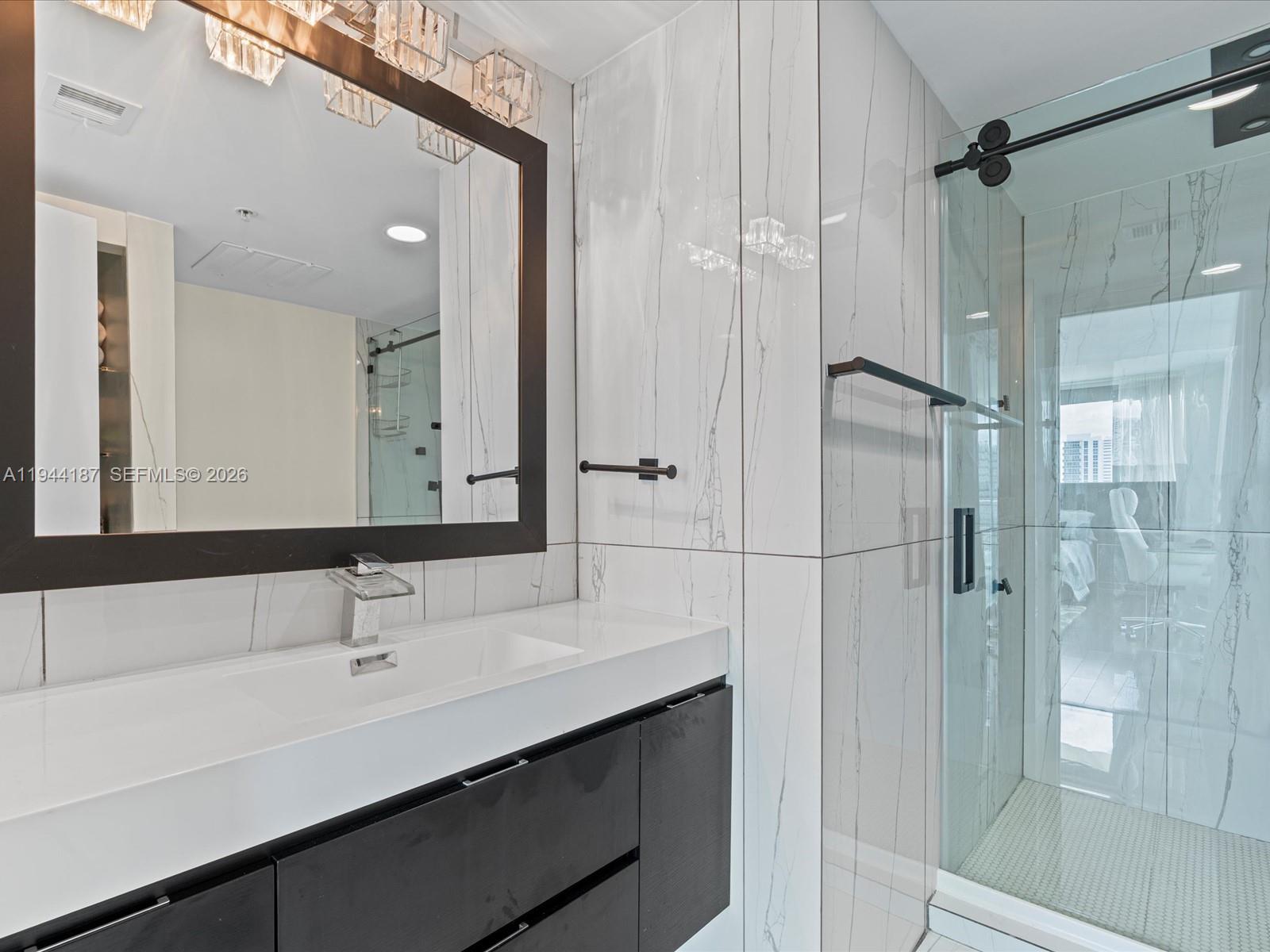 665 Northeast 25th Street, Unit 1101 Miami, FL 33137 - Photo 30 of 47 a bathroom with a double vanity sink mirror and shower