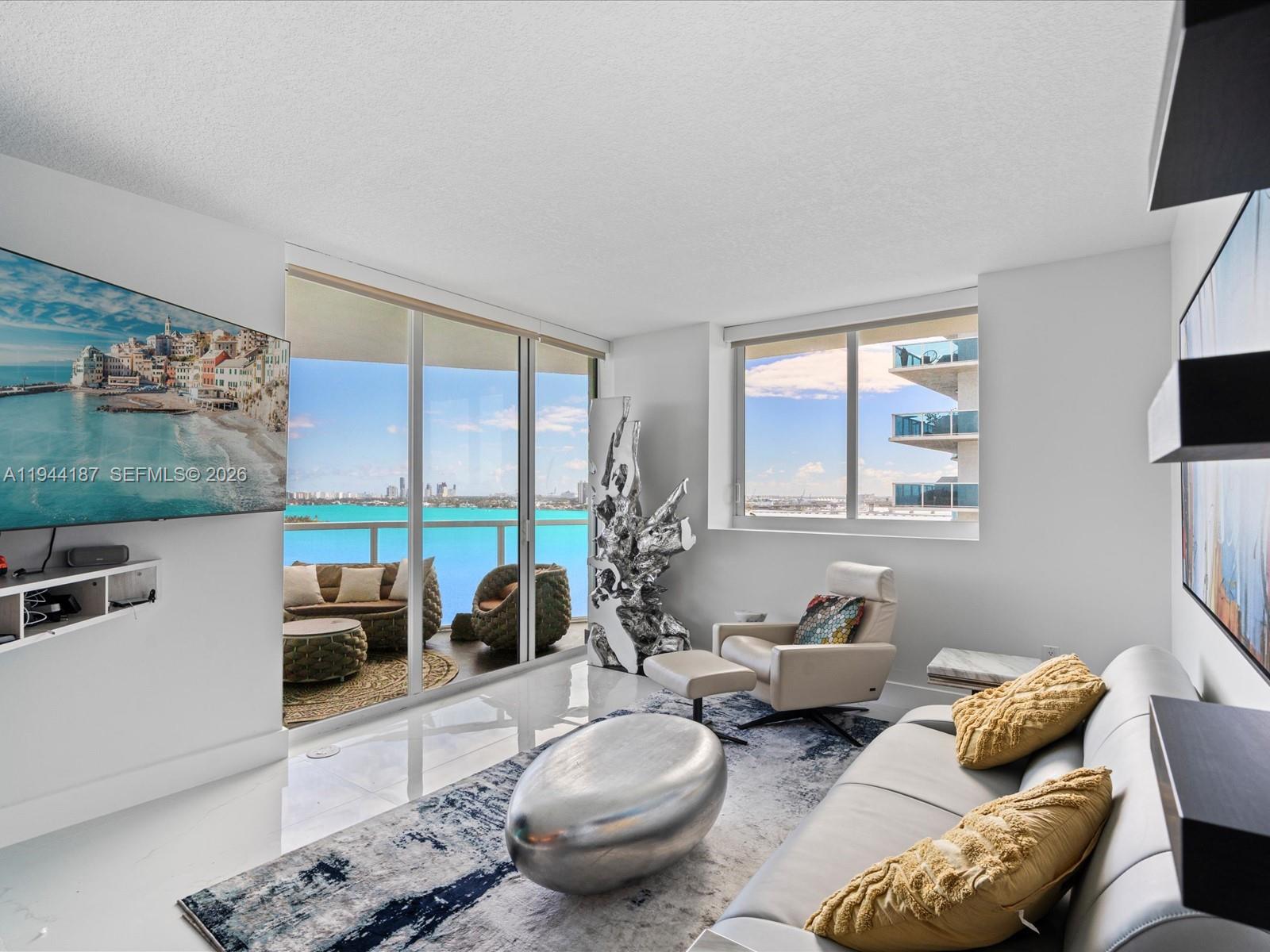 665 Northeast 25th Street, Unit 1101 Miami, FL 33137 - Photo 7 of 47 a living room with furniture a flat screen tv and a floor to ceiling window