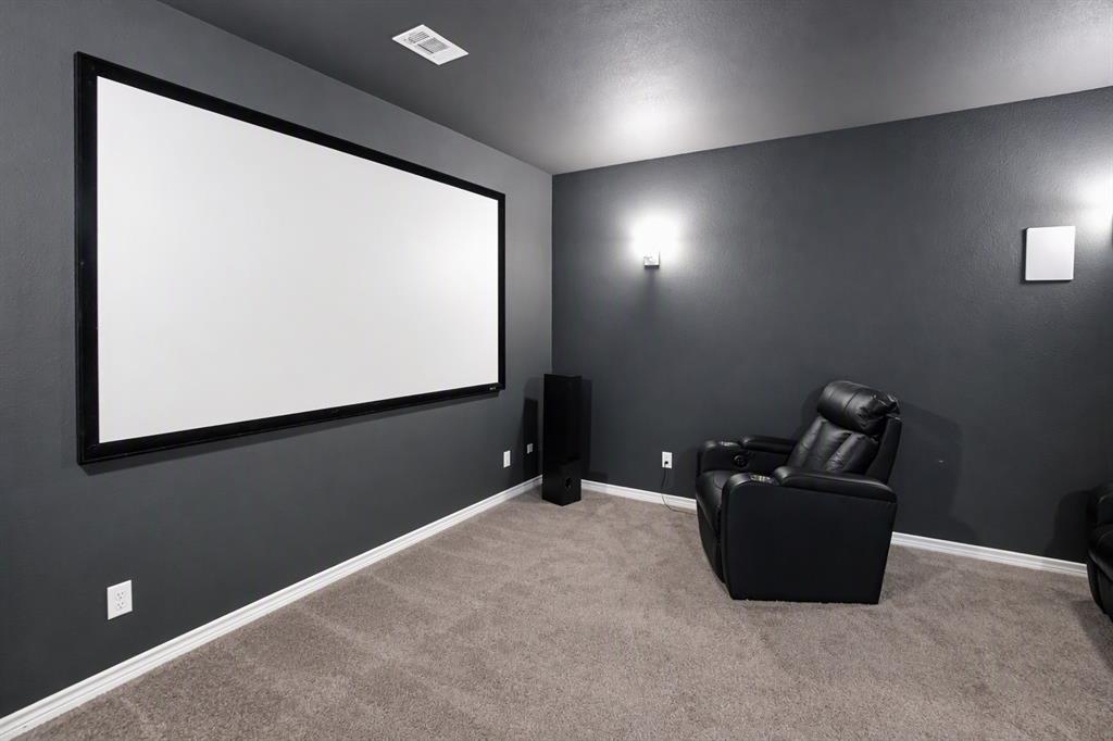 475 Massey Road Gunter, TX 75058 - Photo 25 of 34 Dedicated media room featuring a large projection screen, dark painted walls, and wall-mounted sconces