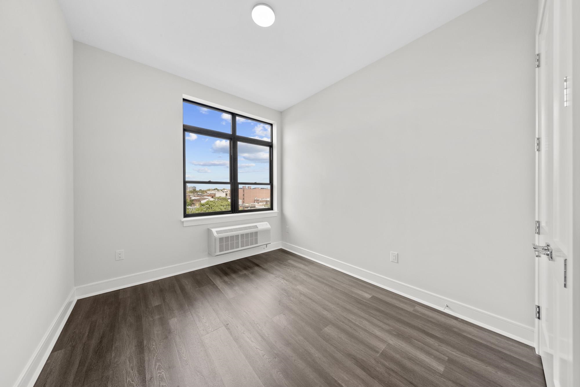 121 34th Street, Unit 401 Union City, NJ 07087 - Photo 14 of 44 an empty room with wooden floor and windows