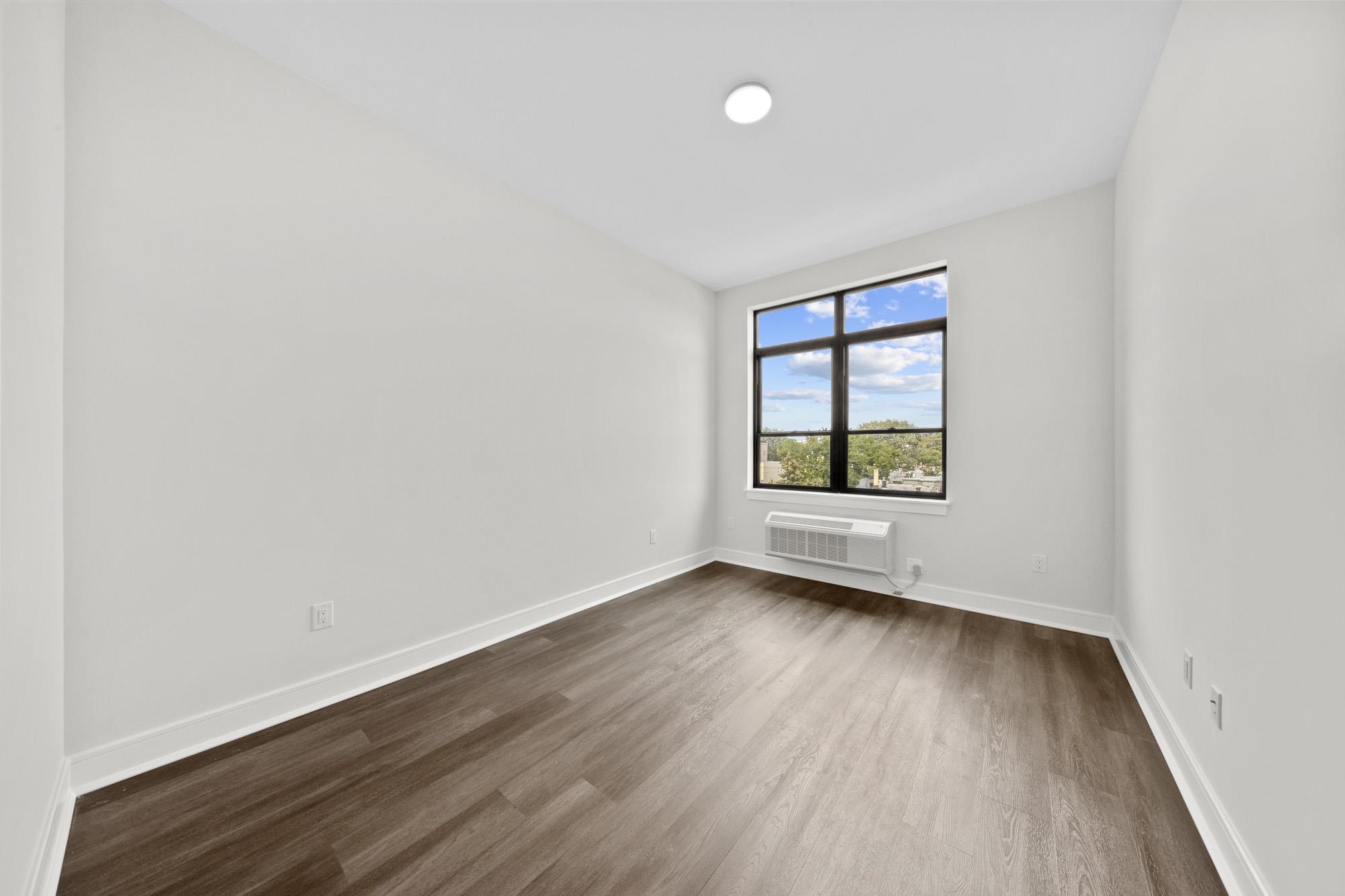 121 34th Street, Unit 401 Union City, NJ 07087 - Photo 17 of 44 an empty room with wooden floor and windows
