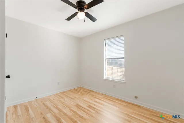 an empty room with a window and a ceiling fan