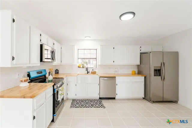 a kitchen with a sink a stove a refrigerator and white cabinets