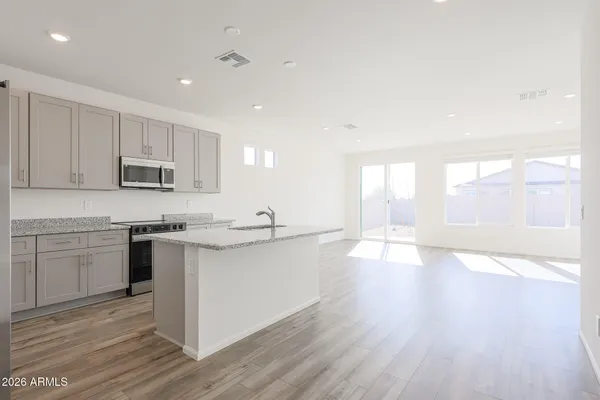a kitchen with stainless steel appliances granite countertop a sink a stove a refrigerator and white cabinets with wooden floor