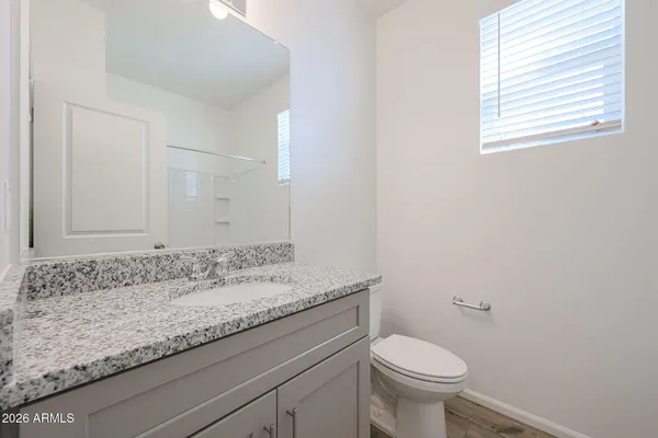a bathroom with a granite countertop sink a toilet and a mirror