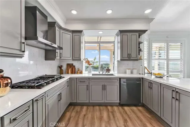 a kitchen with stainless steel appliances granite countertop a stove a sink dishwasher and white cabinets with wooden floor