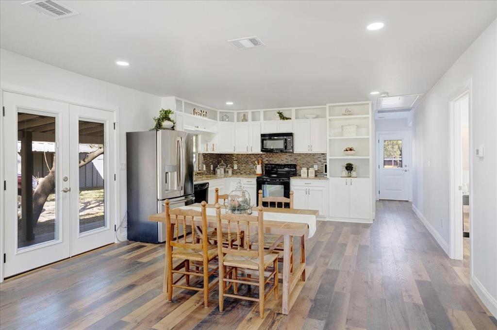 402 West Sam Rayburn Drive Ector, TX 75439 - Photo 19 of 40 a kitchen with stainless steel appliances kitchen island wooden floors and white cabinets
