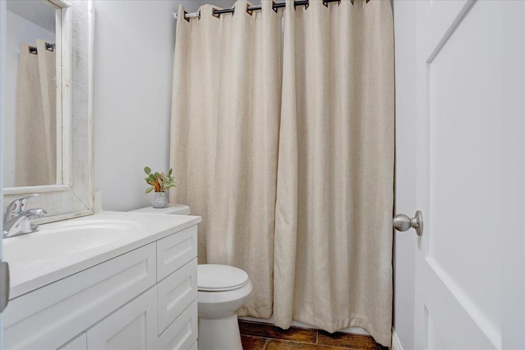 402 West Sam Rayburn Drive Ector, TX 75439 - Photo 27 of 40 a bathroom with a sink a toilet and shower curtain