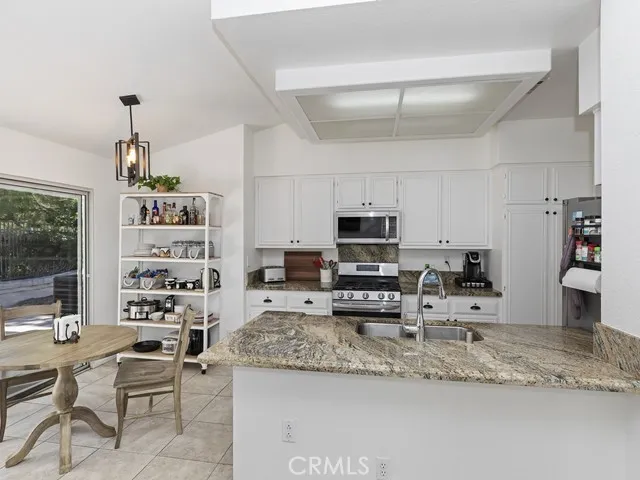 a kitchen with granite countertop a sink a counter top space appliances and cabinets