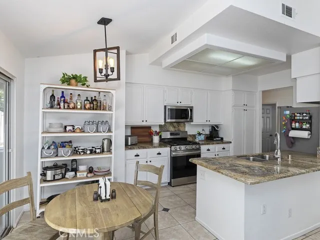 a kitchen with kitchen island stainless steel appliances a sink a stove a table and chairs