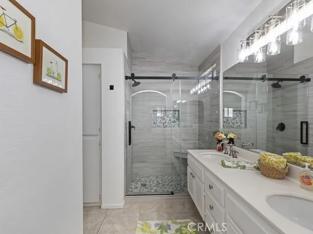 a bathroom with a granite countertop double vanity sink a mirror and shower