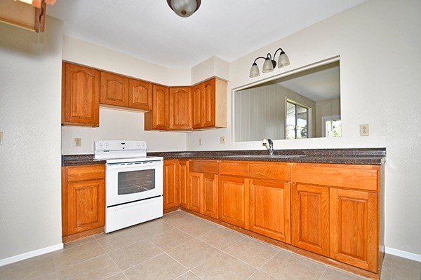 17-239 Volcano Road Keaau, HI 96749 - Photo 9 of 25 a white kitchen with stainless steel appliances granite countertop a stove a sink and a microwave