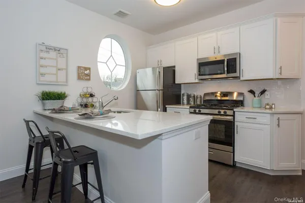 a kitchen with stainless steel appliances a table chairs microwave and cabinets