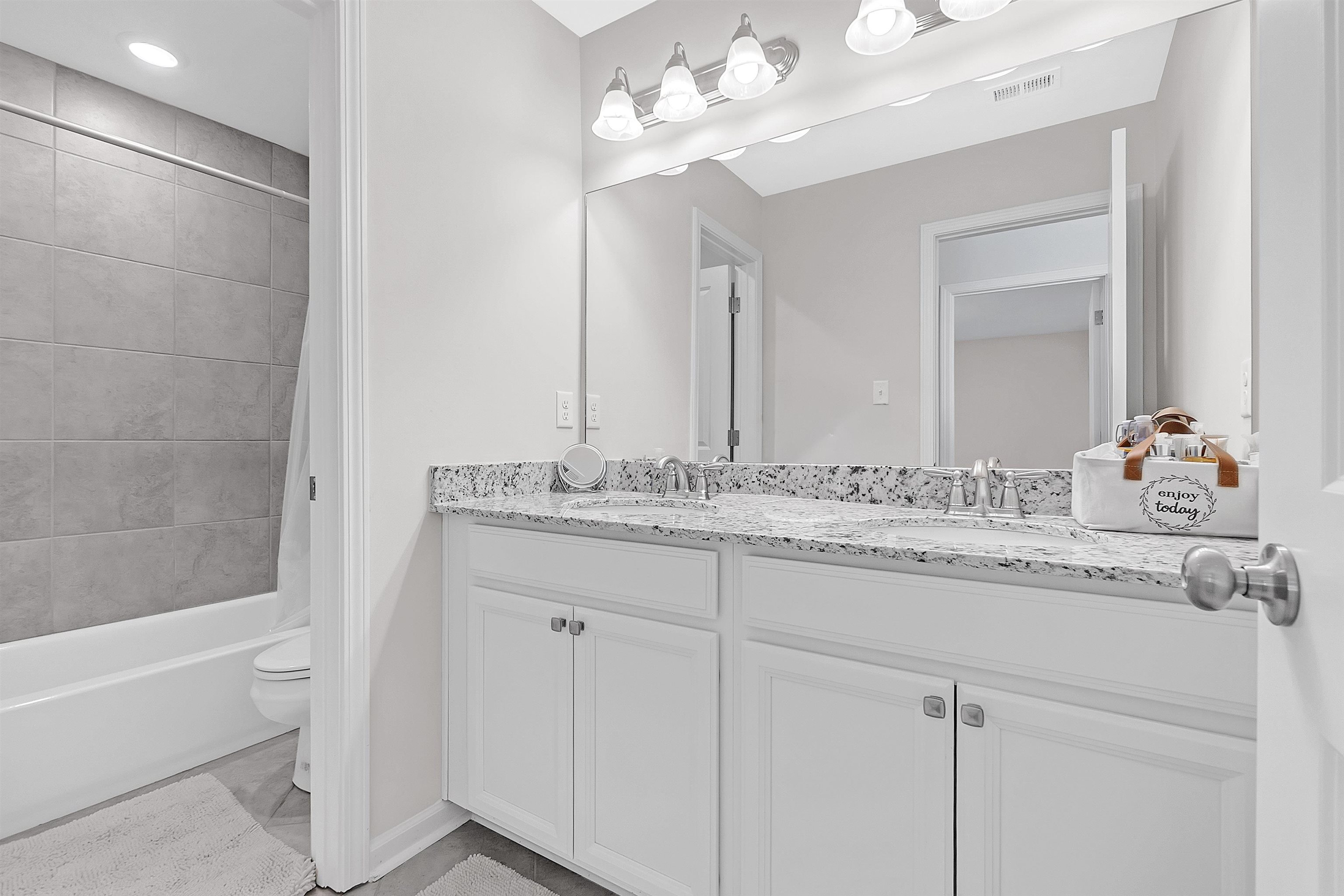 10151 Macon Road Cordova, TN 38018 - Photo 25 of 36 a bathroom with a granite countertop sink a large mirror and a bathtub with shower