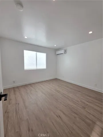 a view of an empty room with wooden floor and closet
