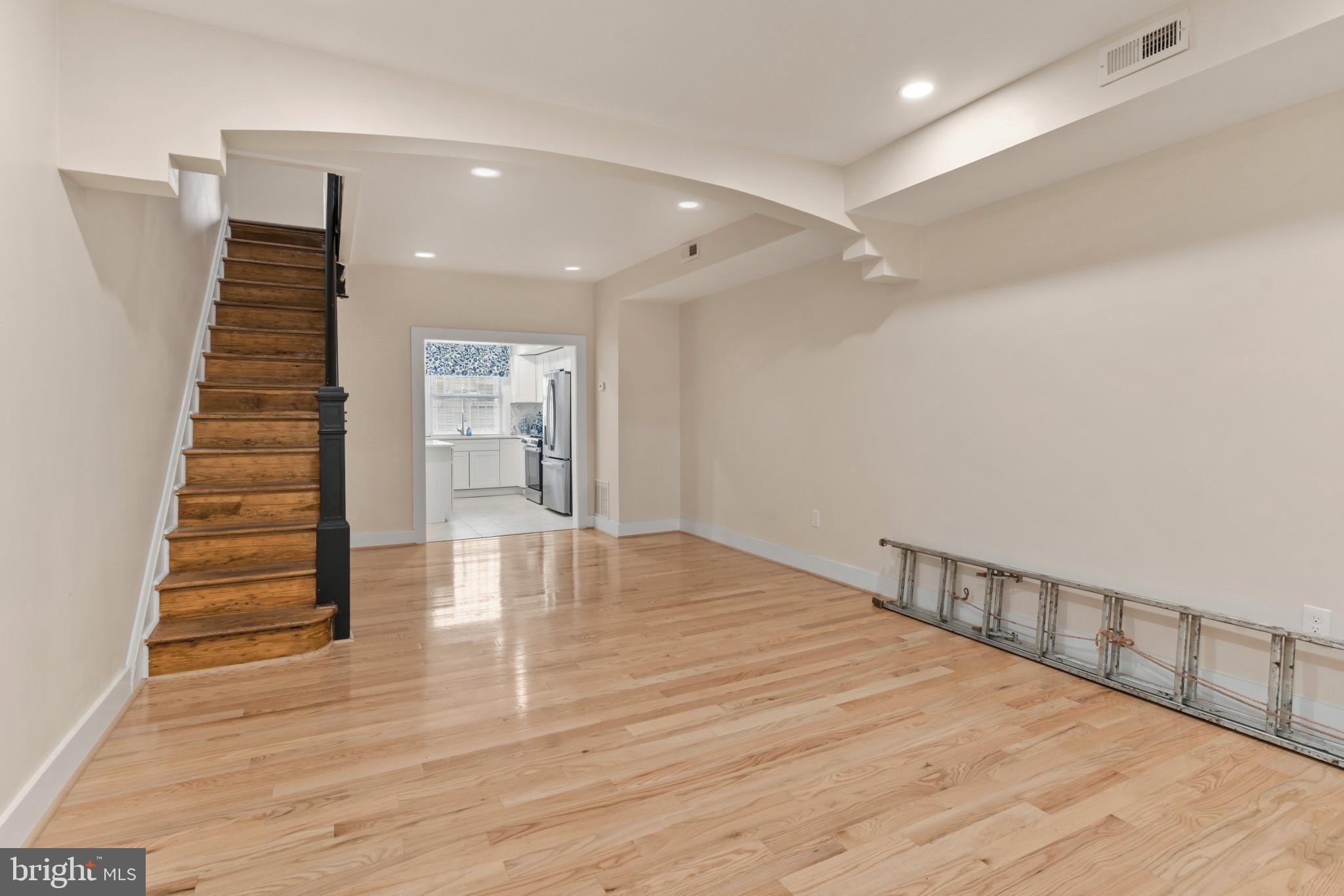 2609 East Hoffman Street Baltimore, MD 21213 - Photo 4 of 22 a view of an empty room with wooden floor and stairs