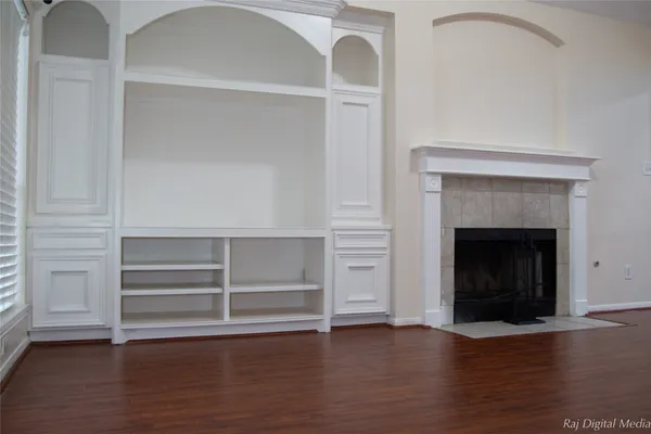 a view of an empty room with a fireplace and wooden floor
