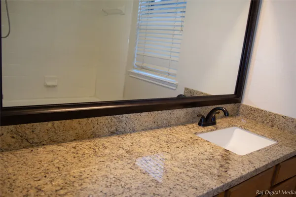 a bathroom with a granite countertop sink and a mirror