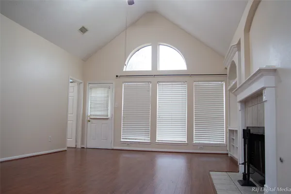 an empty room with wooden floor closet and windows
