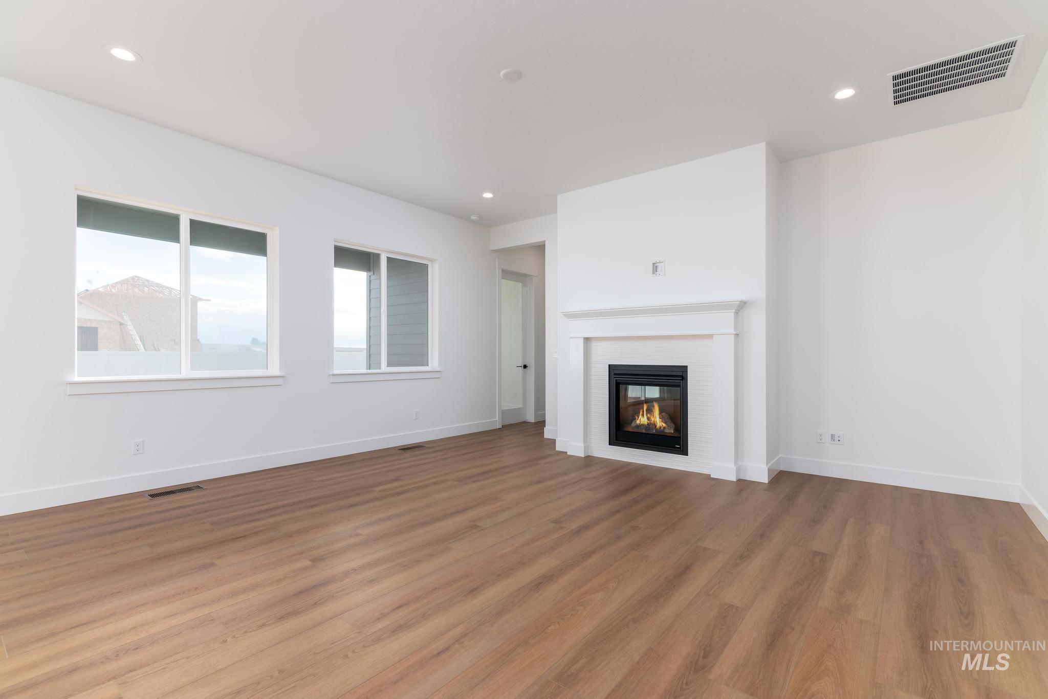 15142 Steel Cloud Avenue Caldwell, ID 83607 - Photo 4 of 34 Unfurnished living room with light wood-type flooring, recessed lighting, and a glass covered fireplace