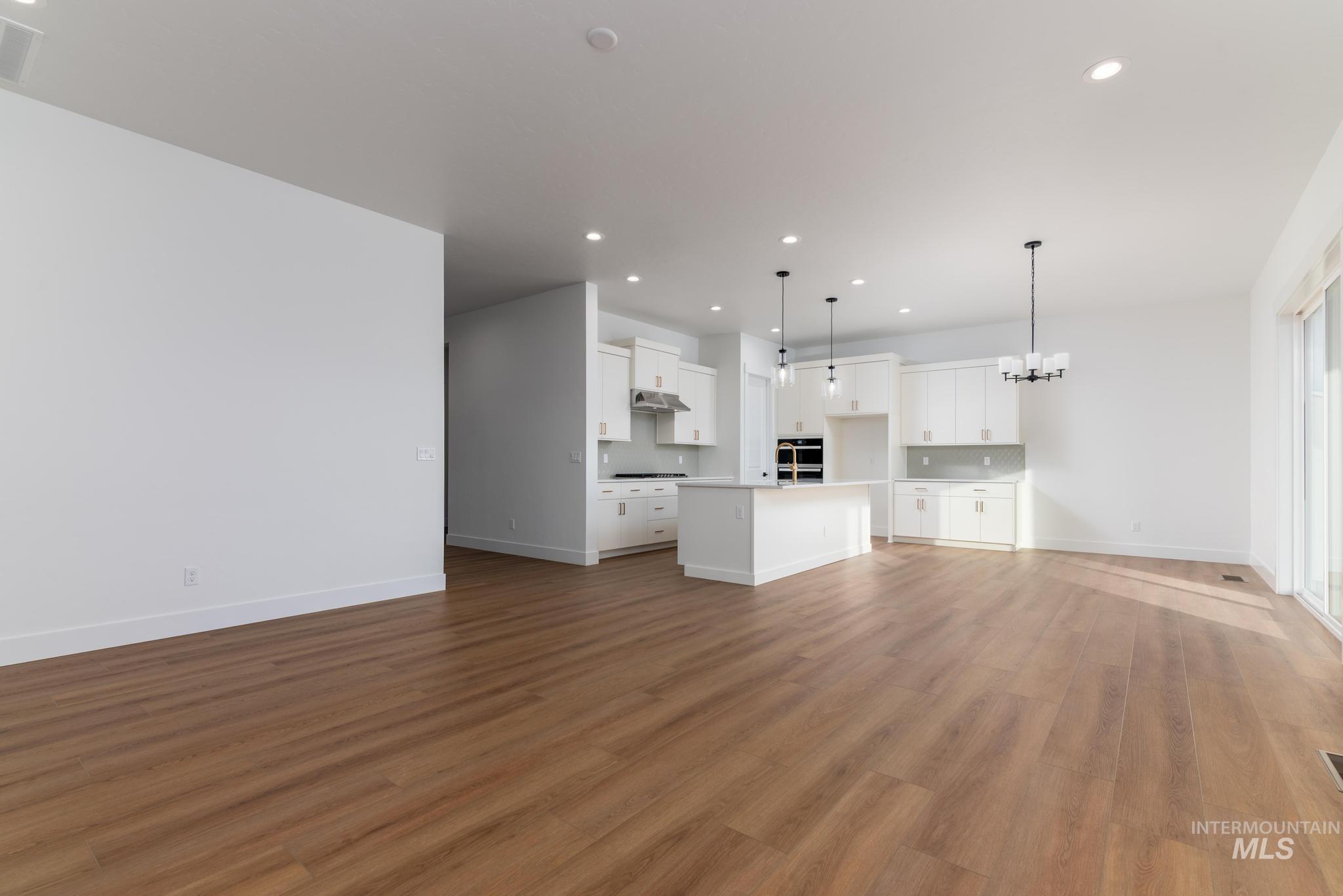 15142 Steel Cloud Avenue Caldwell, ID 83607 - Photo 6 of 34 Unfurnished living room featuring hanging lights and light wood-style floors