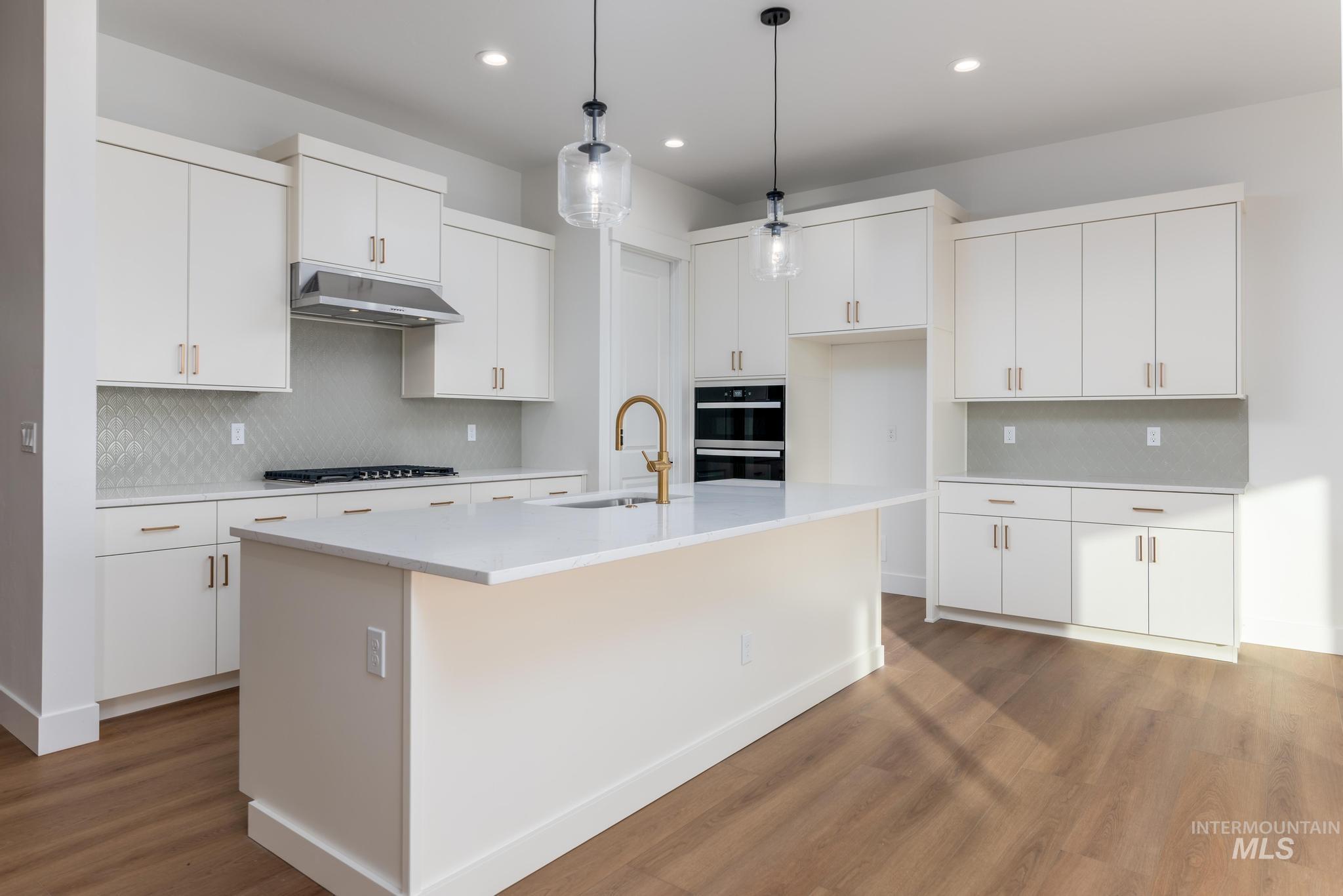 15142 Steel Cloud Avenue Caldwell, ID 83607 - Photo 8 of 34 Kitchen with hanging light fixtures, dark wood-type flooring, a kitchen island with sink, and white cabinetry