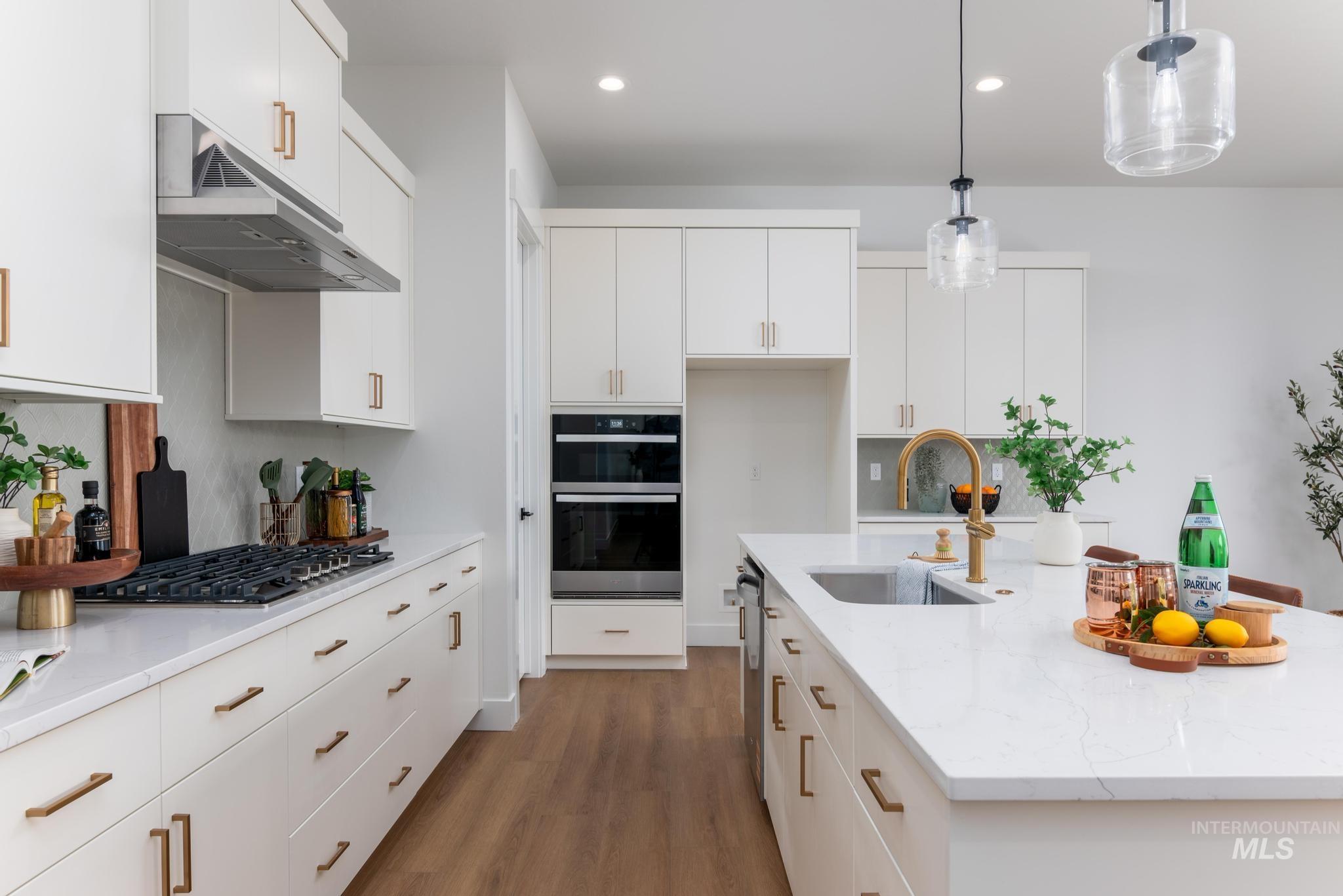 15142 Steel Cloud Avenue Caldwell, ID 83607 - Photo 10 of 44 Kitchen featuring decorative light fixtures, light wood finished floors, white cabinetry, light stone countertops, and stainless steel appliances