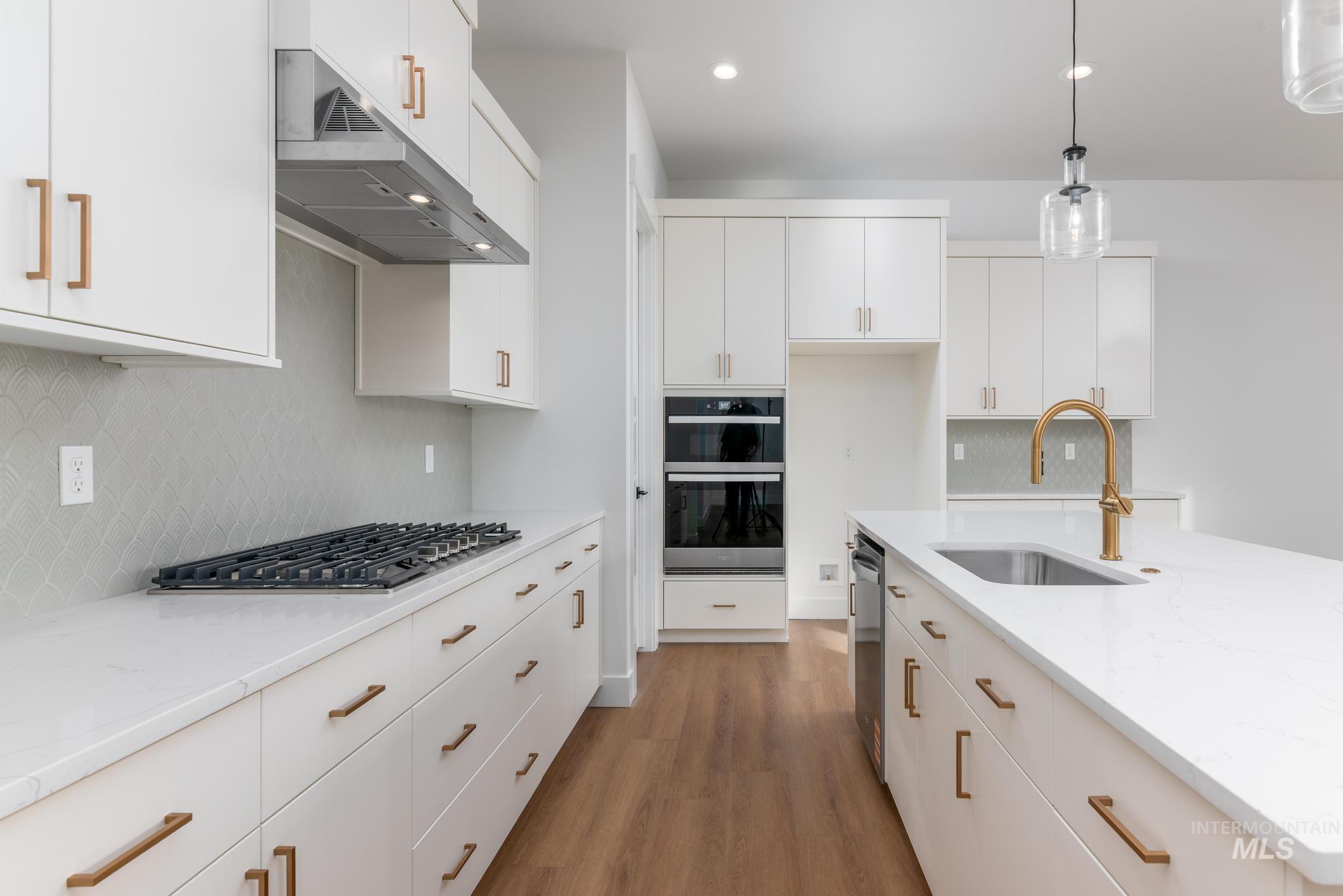 15142 Steel Cloud Avenue Caldwell, ID 83607 - Photo 9 of 34 Kitchen featuring white cabinetry, hanging light fixtures, light wood-style floors, and stainless steel appliances