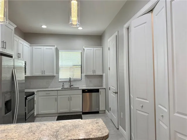 a kitchen with a sink stainless steel appliances cabinets and a window