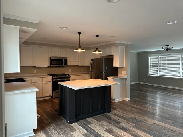 a large kitchen with stainless steel appliances kitchen island granite countertop a sink counter space and a window