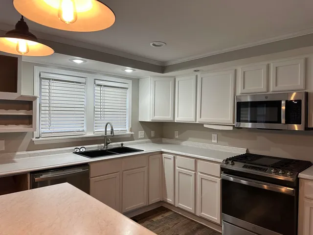 an empty room with wooden floor chandelier and windows