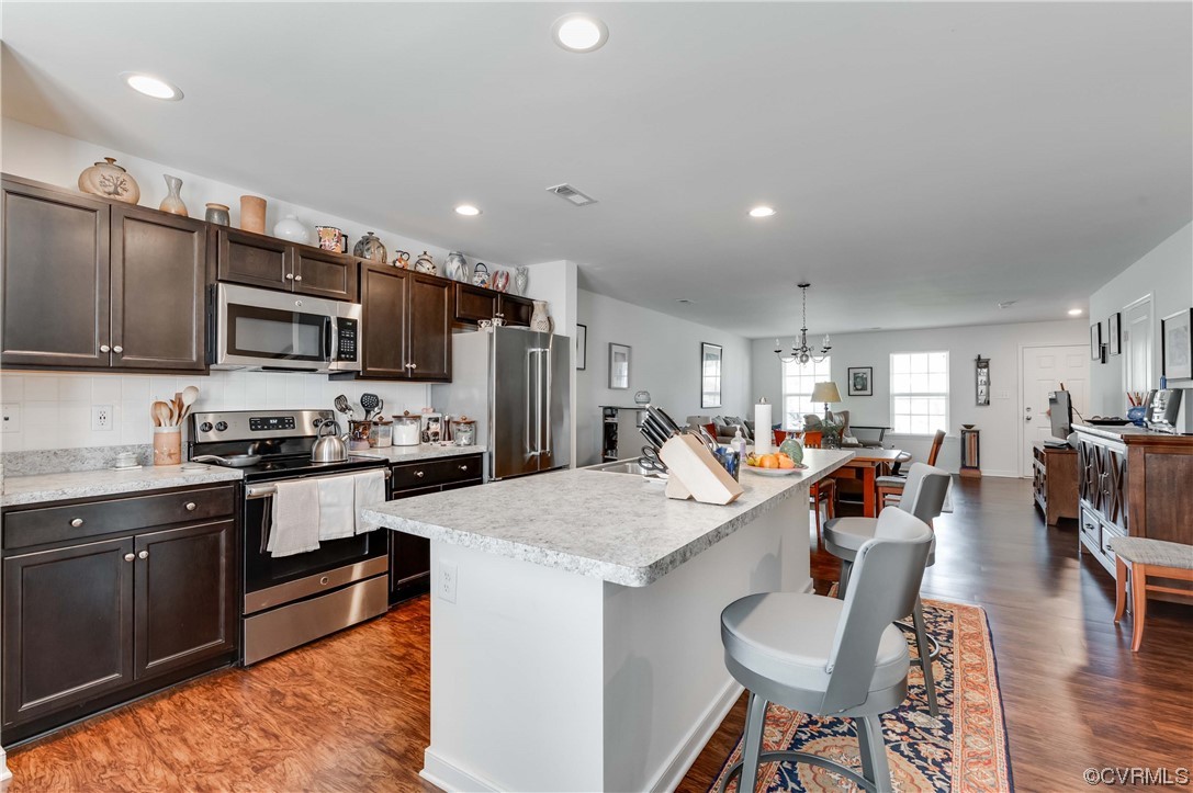 1314 Stone Rdg Pk Loop Henrico, VA 23228 - Photo 10 of 20 Kitchen with a kitchen breakfast bar, a kitchen island, natural light, range oven, refrigerator, microwave, light hardwood floors, and light countertops