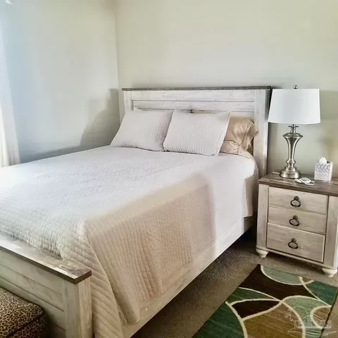 a bedroom with a bed and a lamp on dresser