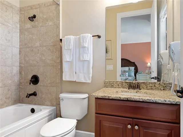 a bathroom with a granite countertop sink toilet and mirror