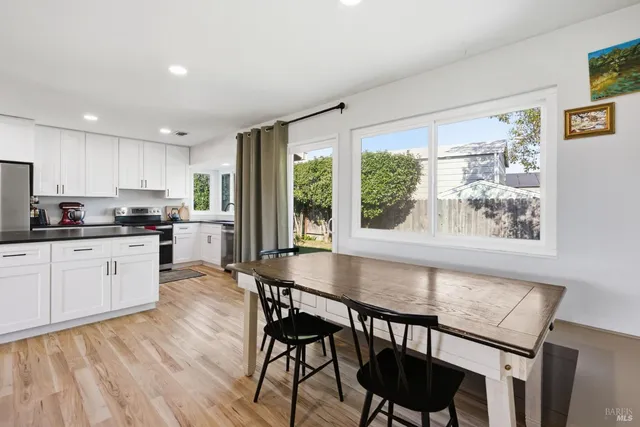 a kitchen with stainless steel appliances granite countertop a stove a refrigerator a microwave a dining table and chairs with wooden floor