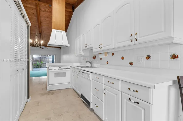 a kitchen with granite countertop a sink stainless steel appliances and white cabinets