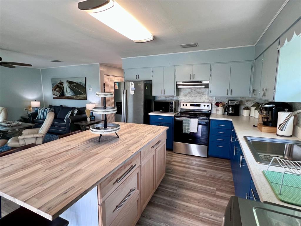 8142 Little Gasparilla Placida, FL 33946 - Photo 11 of 38 a large kitchen with stainless steel appliances wooden floor and a view of living room