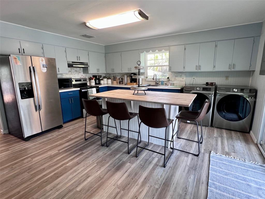 8142 Little Gasparilla Placida, FL 33946 - Photo 13 of 38 a kitchen with stainless steel appliances a table chairs refrigerator microwave and cabinets